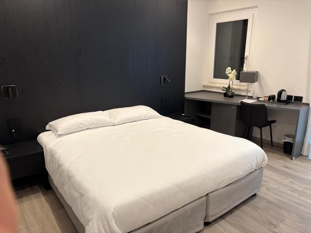 A modern bedroom with a large bed, a desk, and a chair.