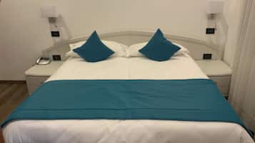 Una habitación de hotel con cama, paredes blancas y una pared azul decorativa.