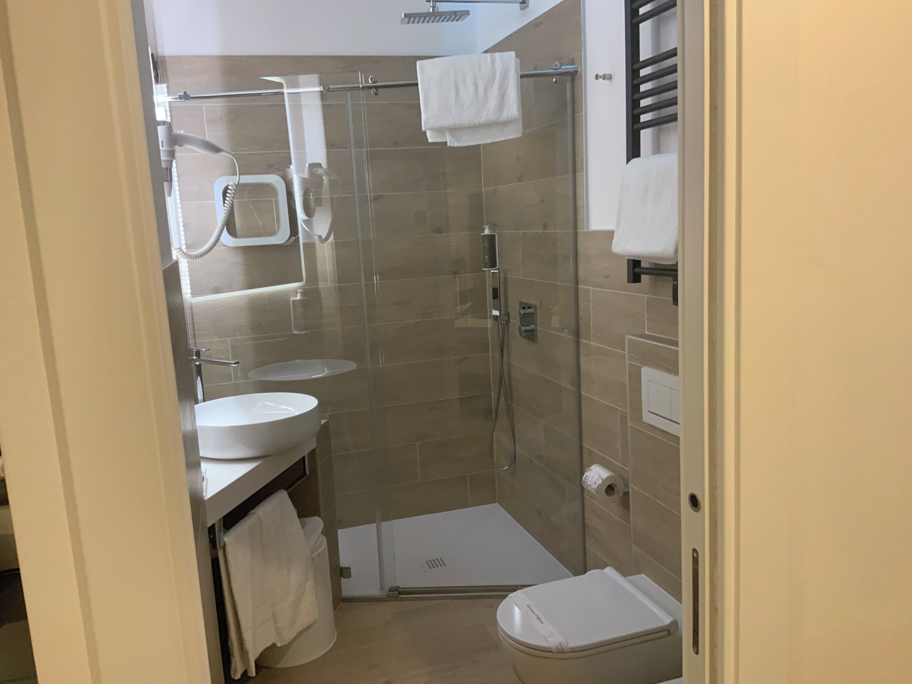 Un baño moderno con ducha de vidrio, lavamanos y retrete.