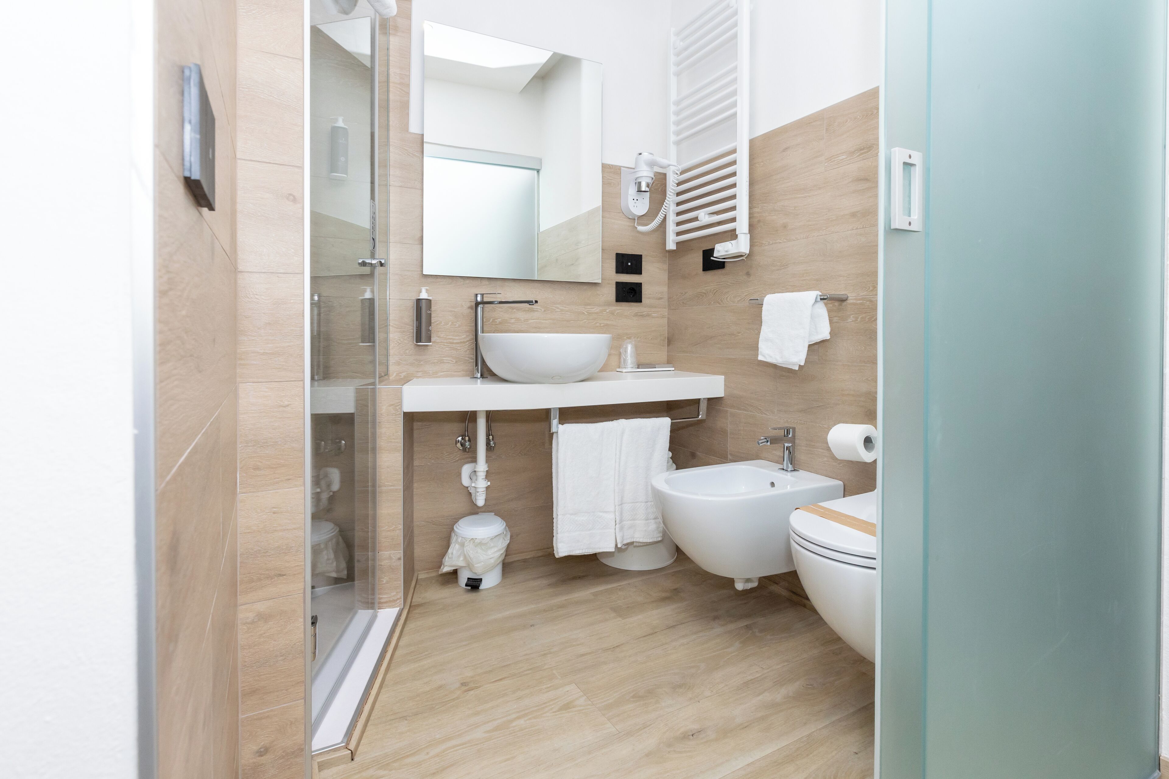 Un bagno moderno con box doccia in vetro, lavandino bianco, bidet e water.