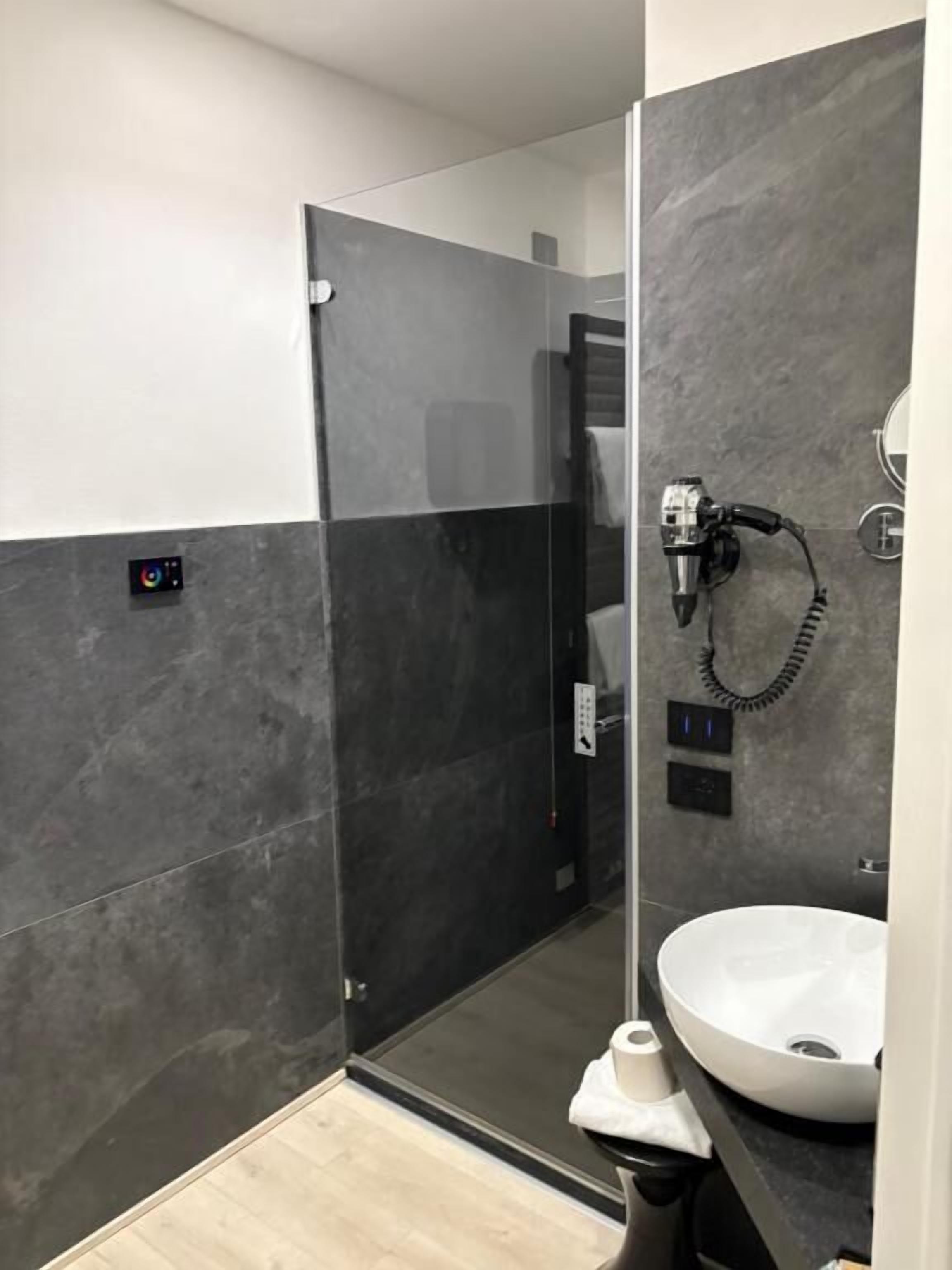 Un baño moderno con ducha a ras de suelo, secador de pelo y lavamanos blanco.
