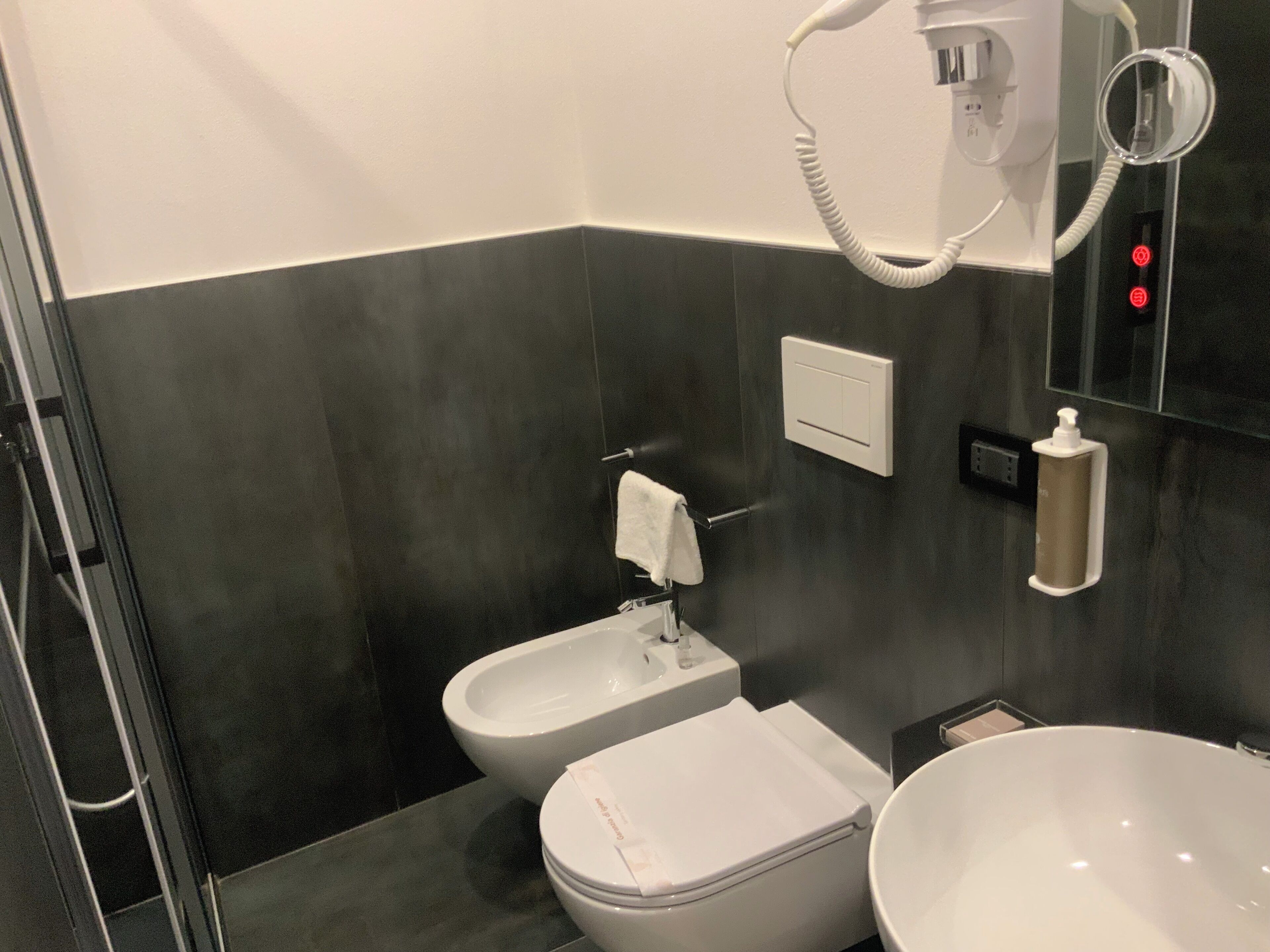 A modern bathroom with a bidet, a toilet, a sink, and a mirror.