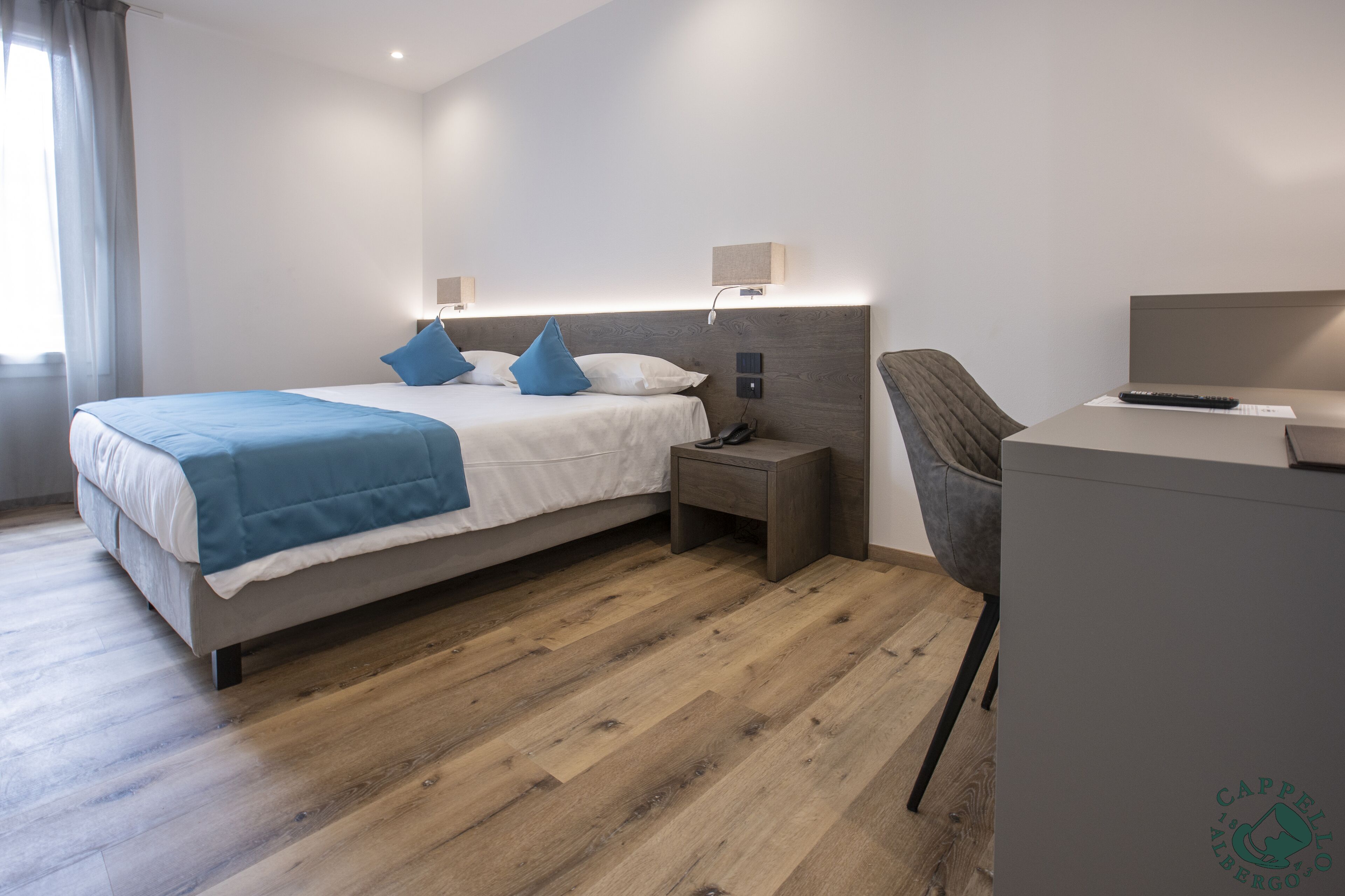 Ein modernes Hotelzimmer mit Bett, Nachttischen, Schreibtisch und Stuhl.
