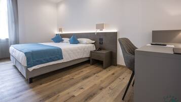 Ein modernes Hotelzimmer mit Bett, Nachttischen, Schreibtisch und Stuhl.