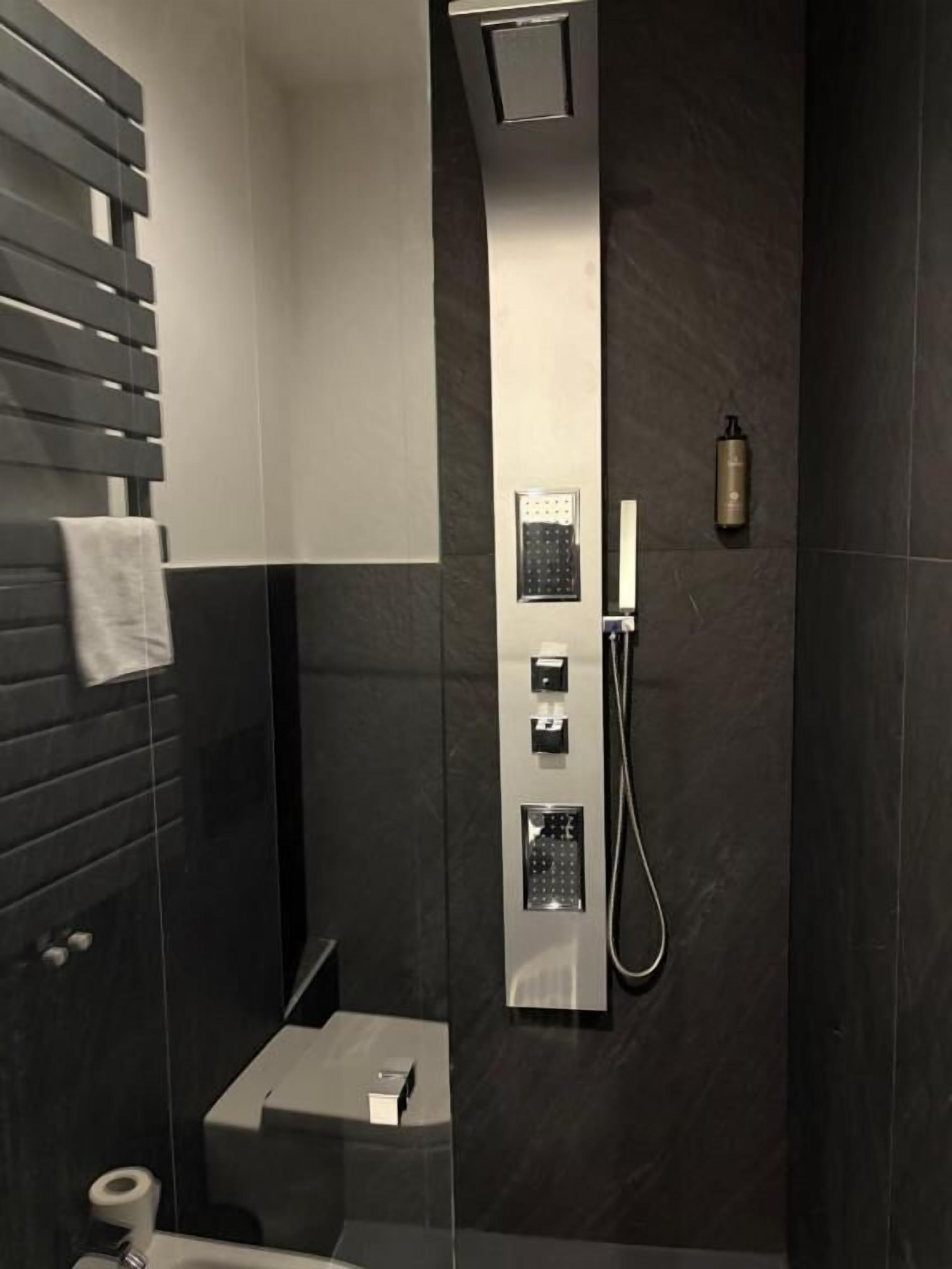 A modern bathroom with a shower, a toilet, and a towel rack.