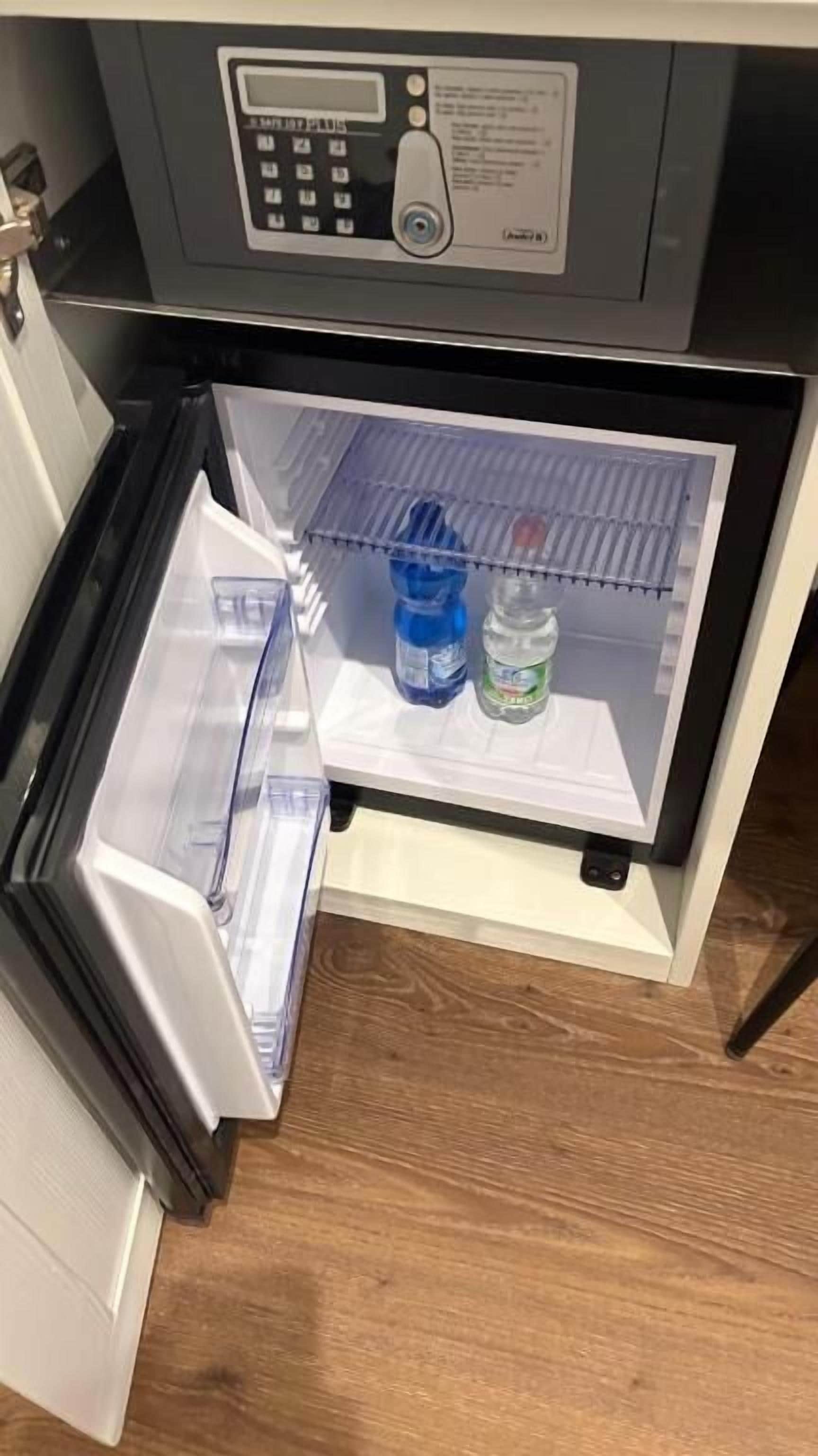 A refrigerator with a control panel, a freezer compartment, and shelves with water bottles.