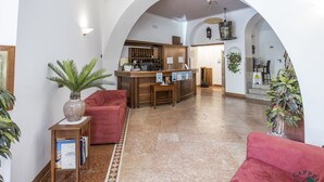 A spacious lobby with a reception desk, seating area, and a kitchen in the background. - Albergo Cappello e Cadore (Belluno)