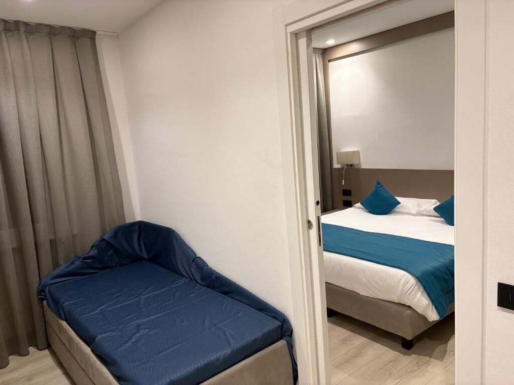 Quarto com uma cama de solteiro, uma mesinha e uma cortina.