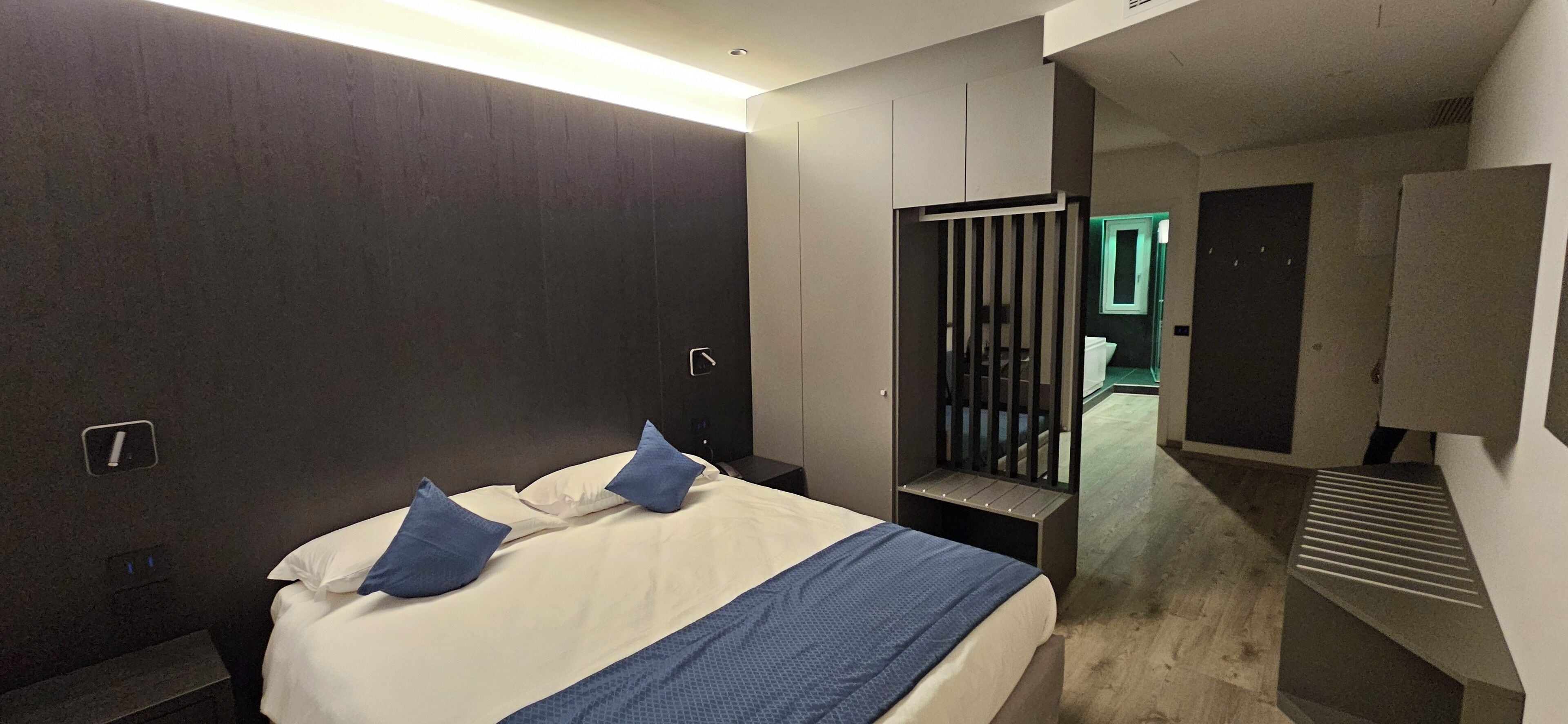Une chambre d’hôtel moderne dotée d’un grand lit, d’un bureau et d’un dressing.
