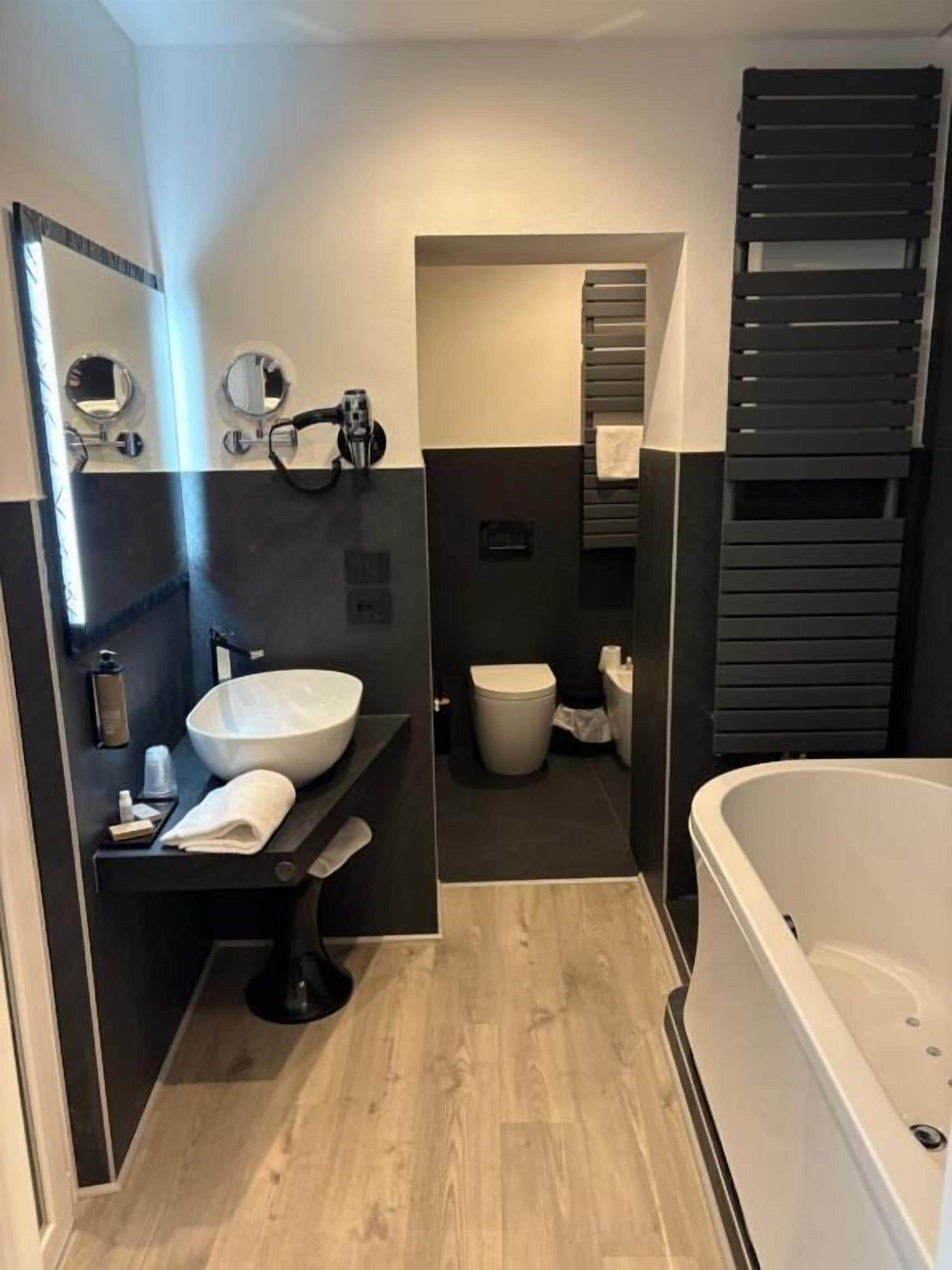 Ein modernes Badezimmer mit einer großen Badewanne, einem runden Waschbecken und einer Toilette.