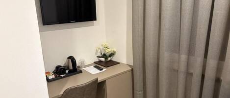 Habitación de hotel con escritorio, silla, televisión y cama.