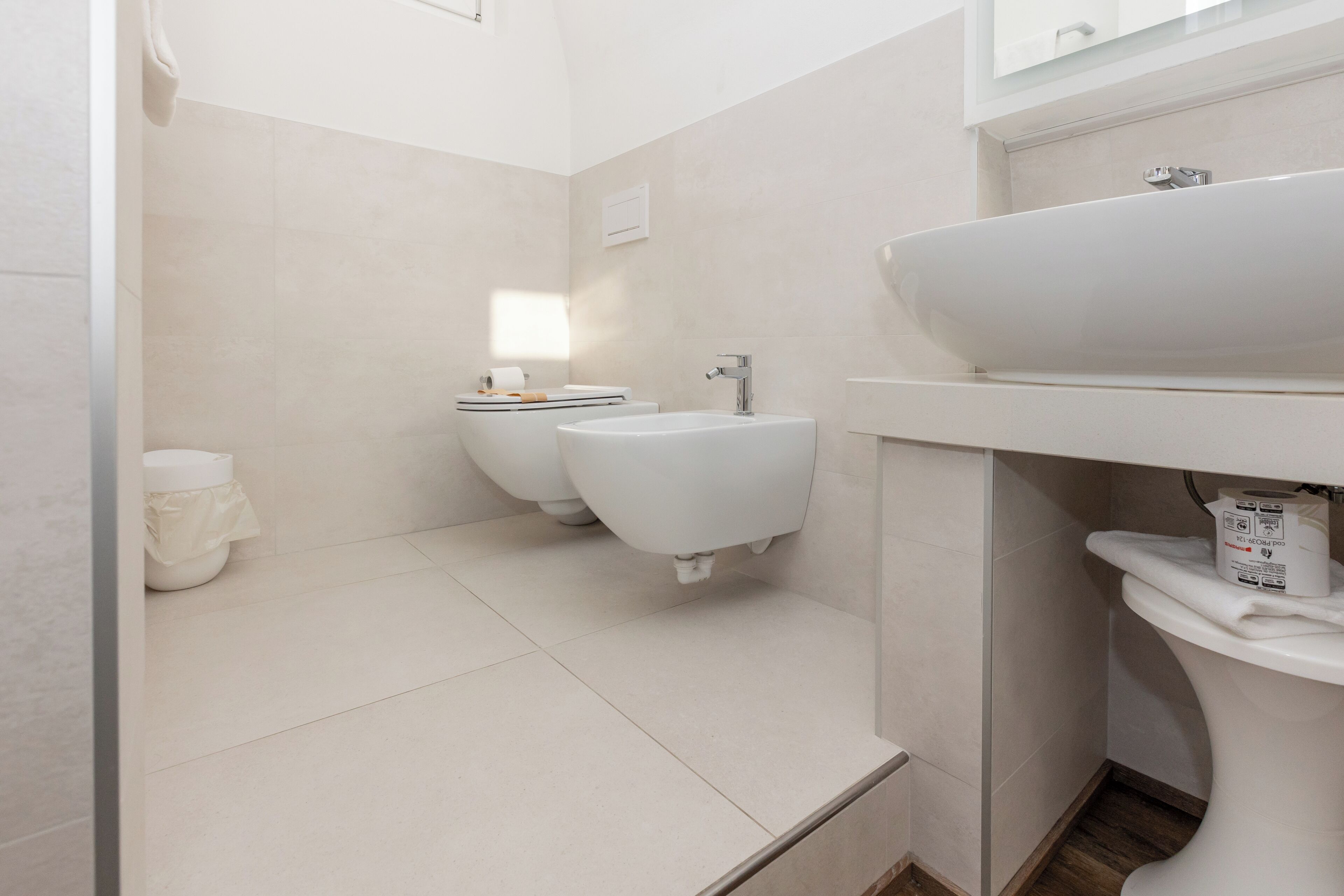 A modern bathroom with a toilet, bidet, and a large sink.