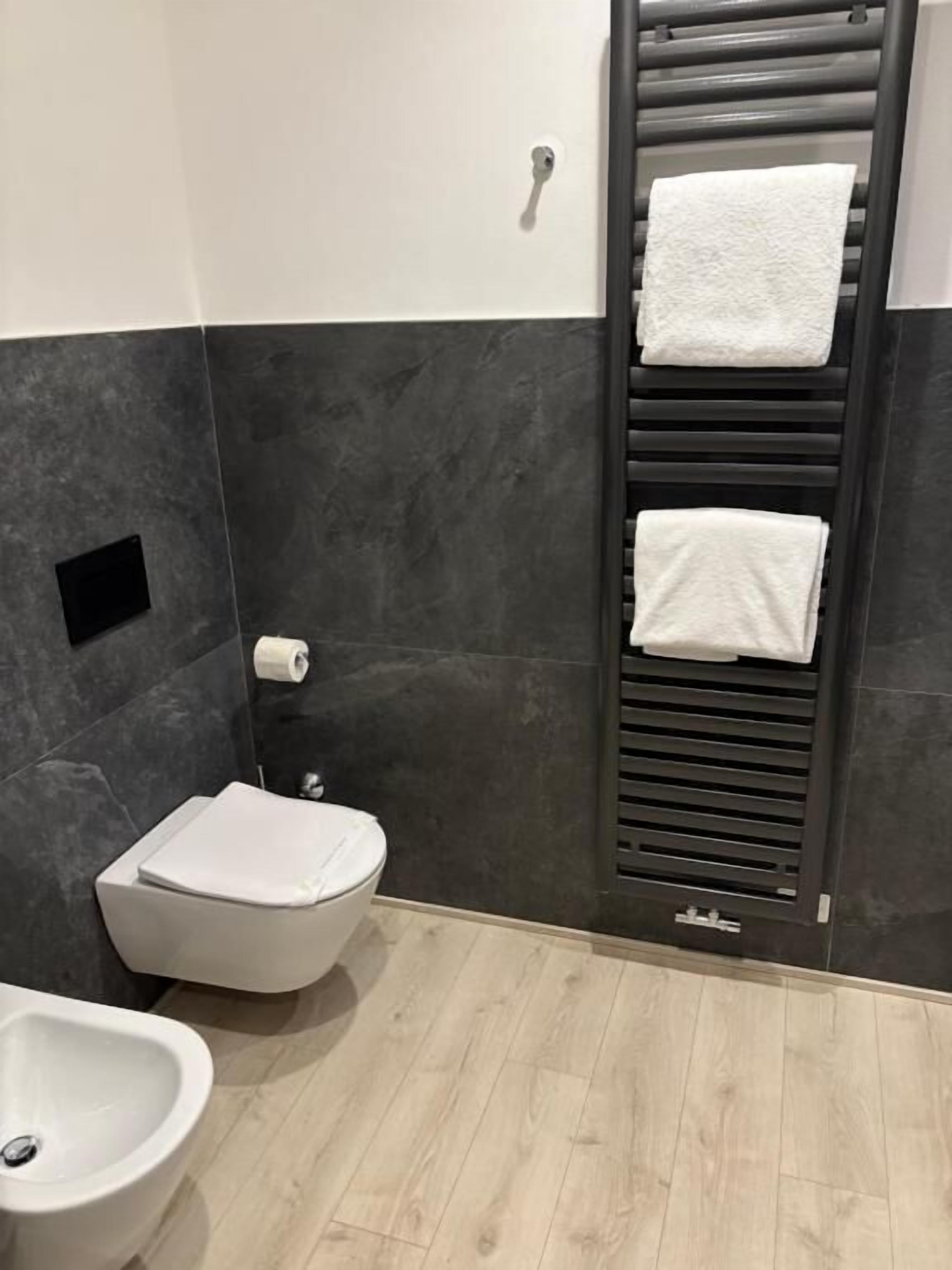Een moderne badkamer met toilet, bidet en handdoekrek.