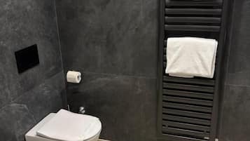 Een moderne badkamer met toilet, bidet en handdoekrek.