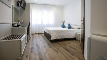 Habitación de hotel con cama, mesita de noche, lámpara y un televisor de pantalla plana en la pared.