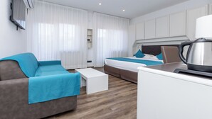 A modern hotel room with a sofa, a bed, a coffee table, and a kettle. - Albergo Cappello e Cadore (Belluno)