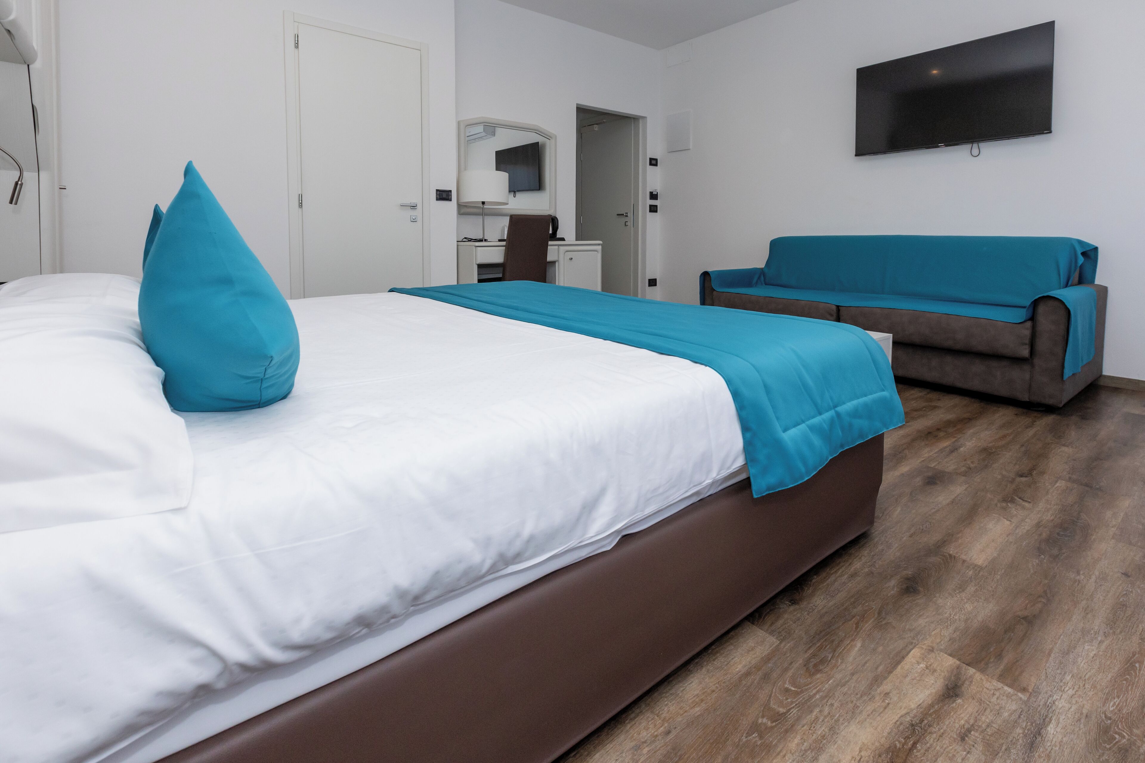 Een hotelkamer met een bed, een slaapbank, een bureau en een televisie.