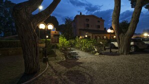 A building with a garden pathway, surrounded by trees and street lamps. - La Pineta dei Liberti (Ardea)