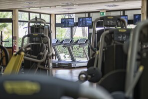 Un gimnasio con cintas de correr, bicicletas estáticas y máquinas de pesas.