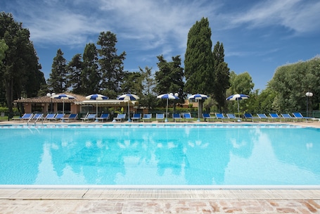 Una piscina al aire libre, sillones reclinables de piscina