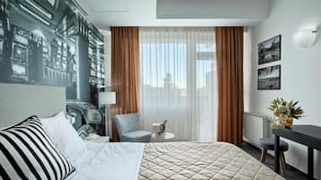A hotel room with a bed, a chair, a small table, a lamp, and a view of the outdoors.