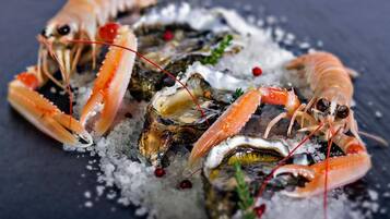 Plat de marisc amb llagosta i ostres sobre gel, guarnit amb herbes i baies vermelles.