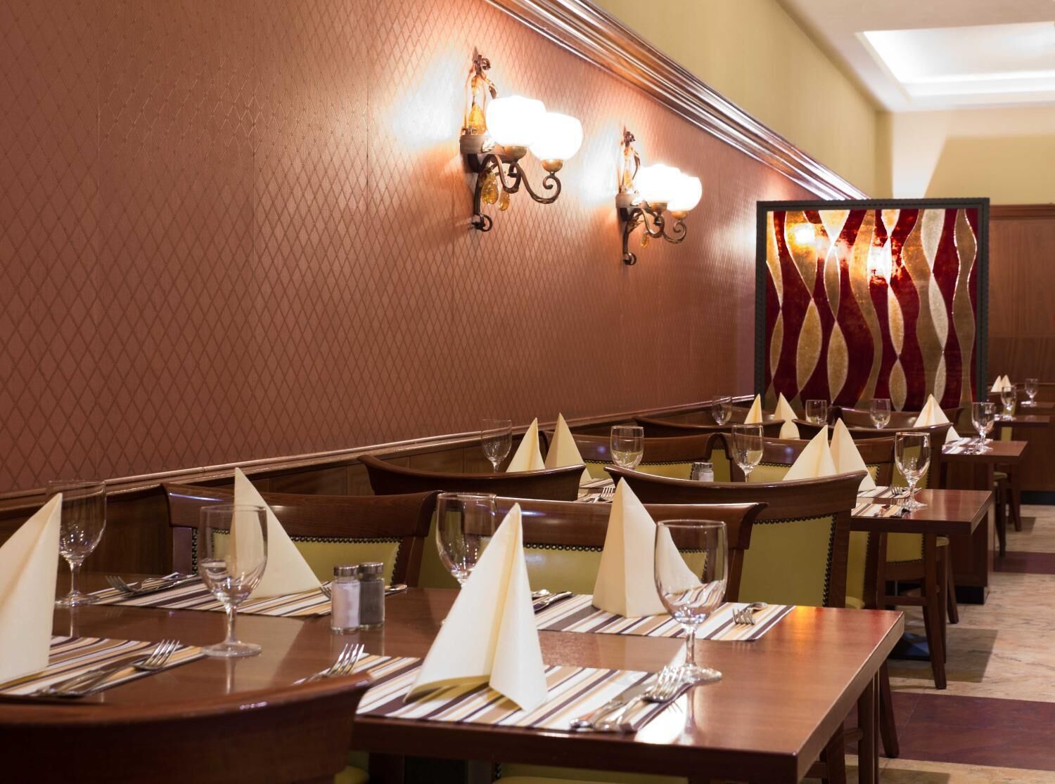 Un restaurant où les tables sont dressées avec des serviettes blanches, des couverts en argent et des verres à vin.