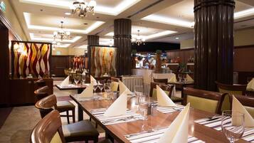 A restaurant with high ceilings, chandeliers, and striped tablecloths.