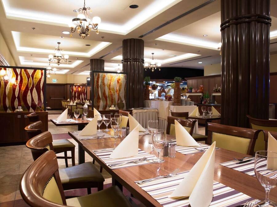 A restaurant with high ceilings, chandeliers, and striped tablecloths.