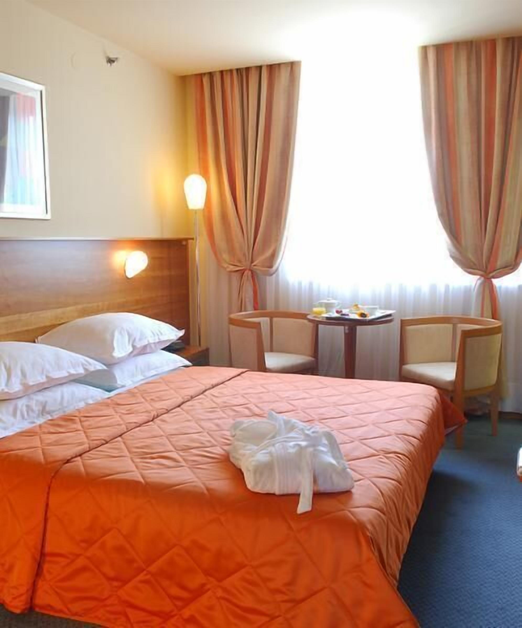 Una habitación de hotel con dos camas, una mesita y dos sillas.