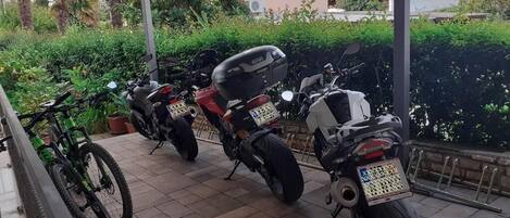 Un espacio al aire libre cubierto con dos motocicletas estacionadas y una bicicleta.