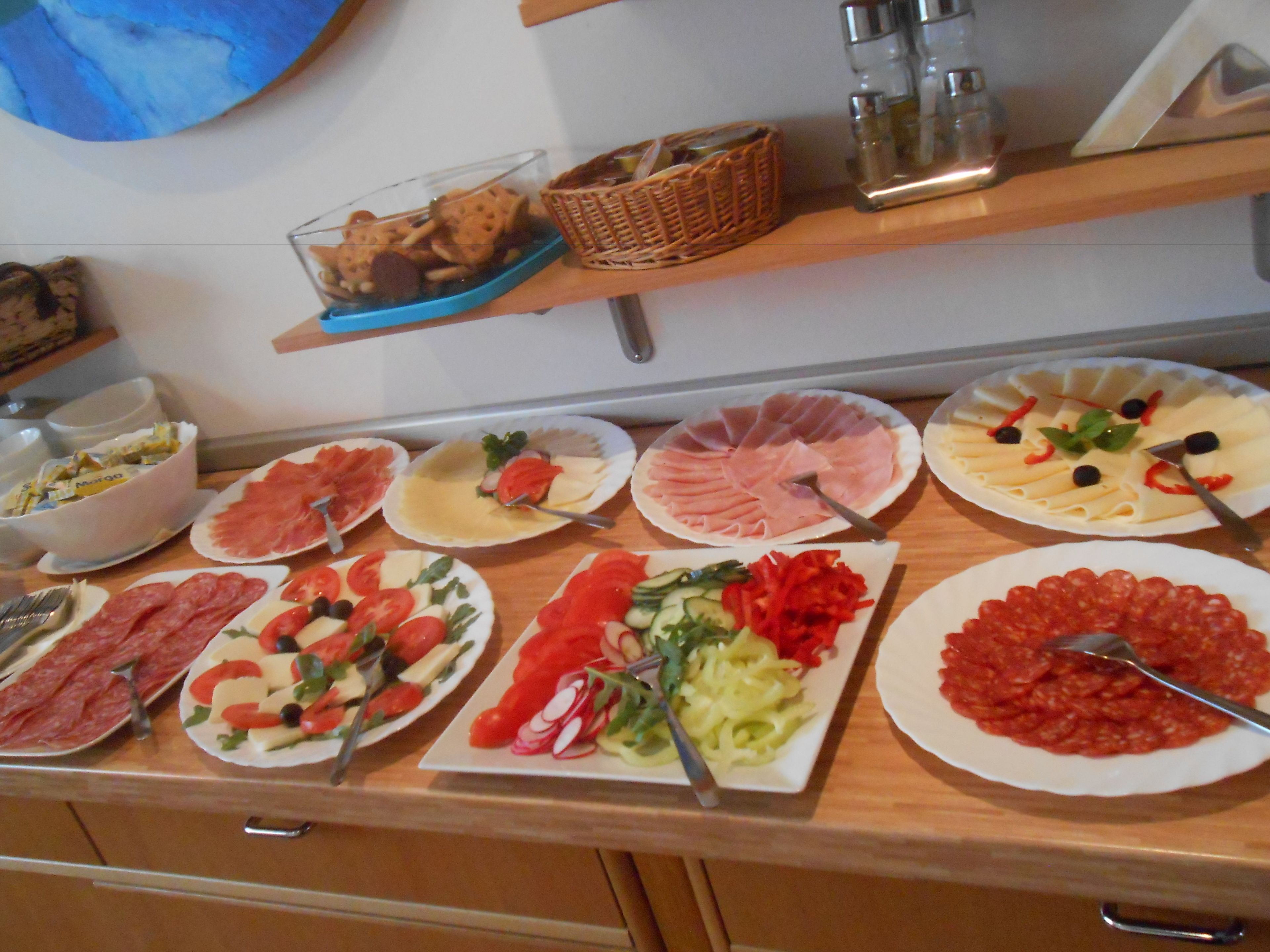 Ein reichhaltiges Buffet mit verschiedenen Speisen, darunter Fleisch, Käse und Salate.