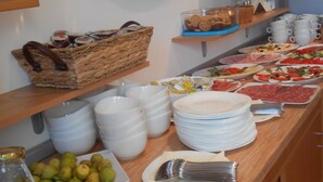 Un buffet proposant une variété d’aliments, notamment des fruits, des pâtisseries et des boissons.