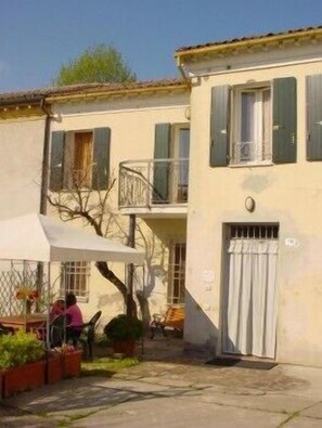A two-story building with a balcony, a covered patio area, and a gated entrance. - Casa Cortesi (Bagnacavallo)