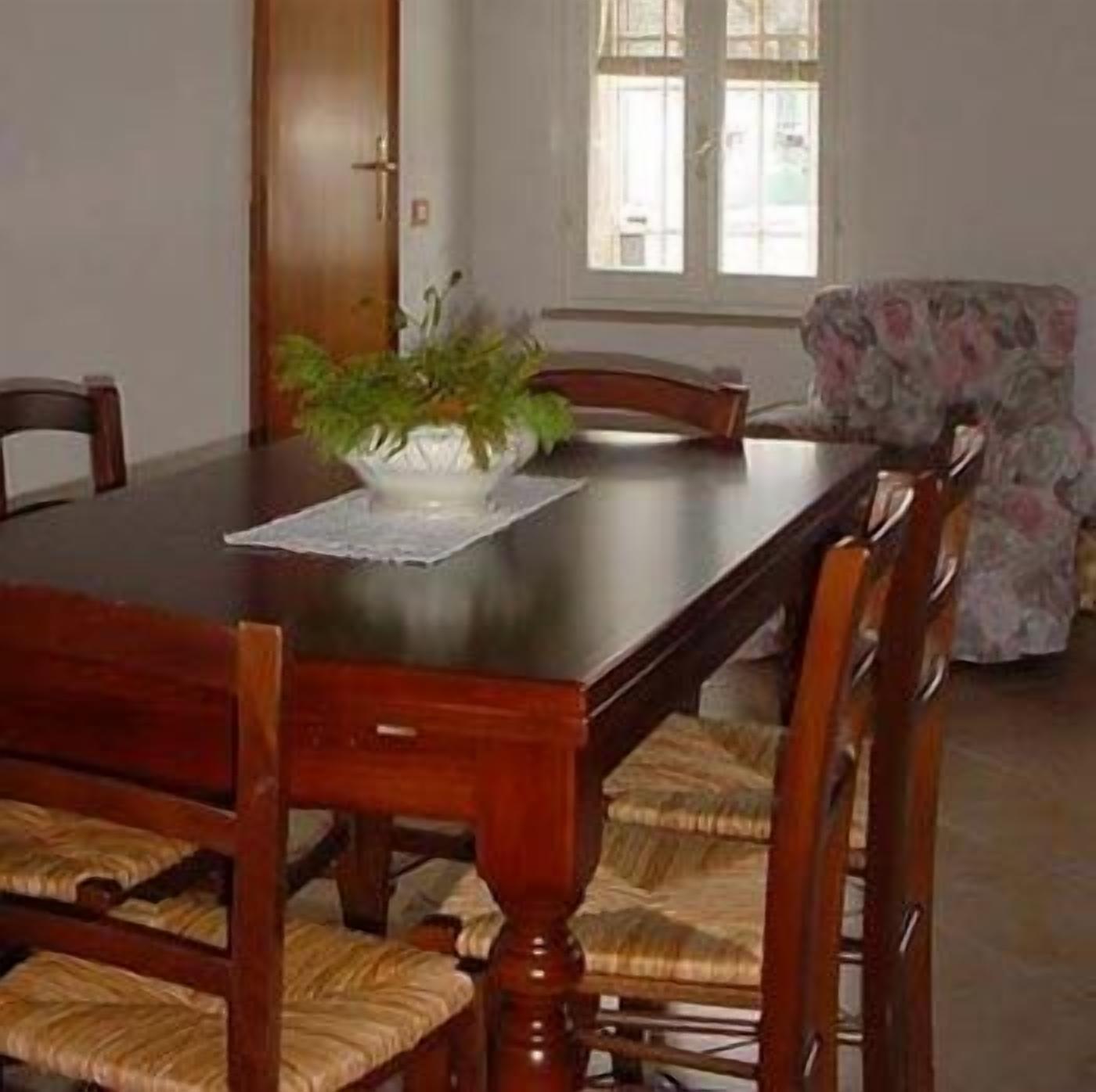 A dining room with a wooden table, chairs, and a floral armchair.