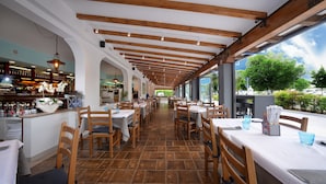A restaurant with wooden beams, tiled flooring, and tables set for dining.
