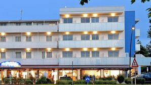 A multi-story hotel with a restaurant on the ground floor, outdoor seating, and a pedestrian crossing sign.