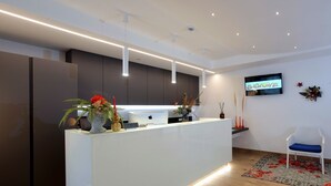 A modern reception area with a white desk, a laptop, and a flat-screen TV displaying 'BIBIONE'.