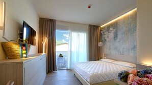 A hotel room with a bed, a desk, a television, and a view of the outdoors.