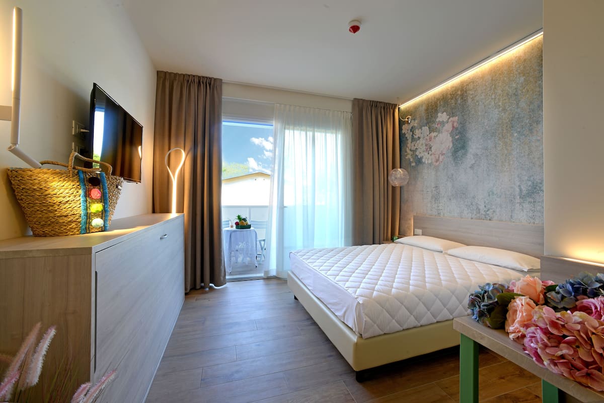 Una habitación de hotel con cama, escritorio, televisión y vistas al exterior.