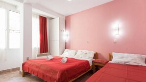 A hotel room with two beds, a red wall, and a window with curtains. - Apartments Kosta (Ohrid)