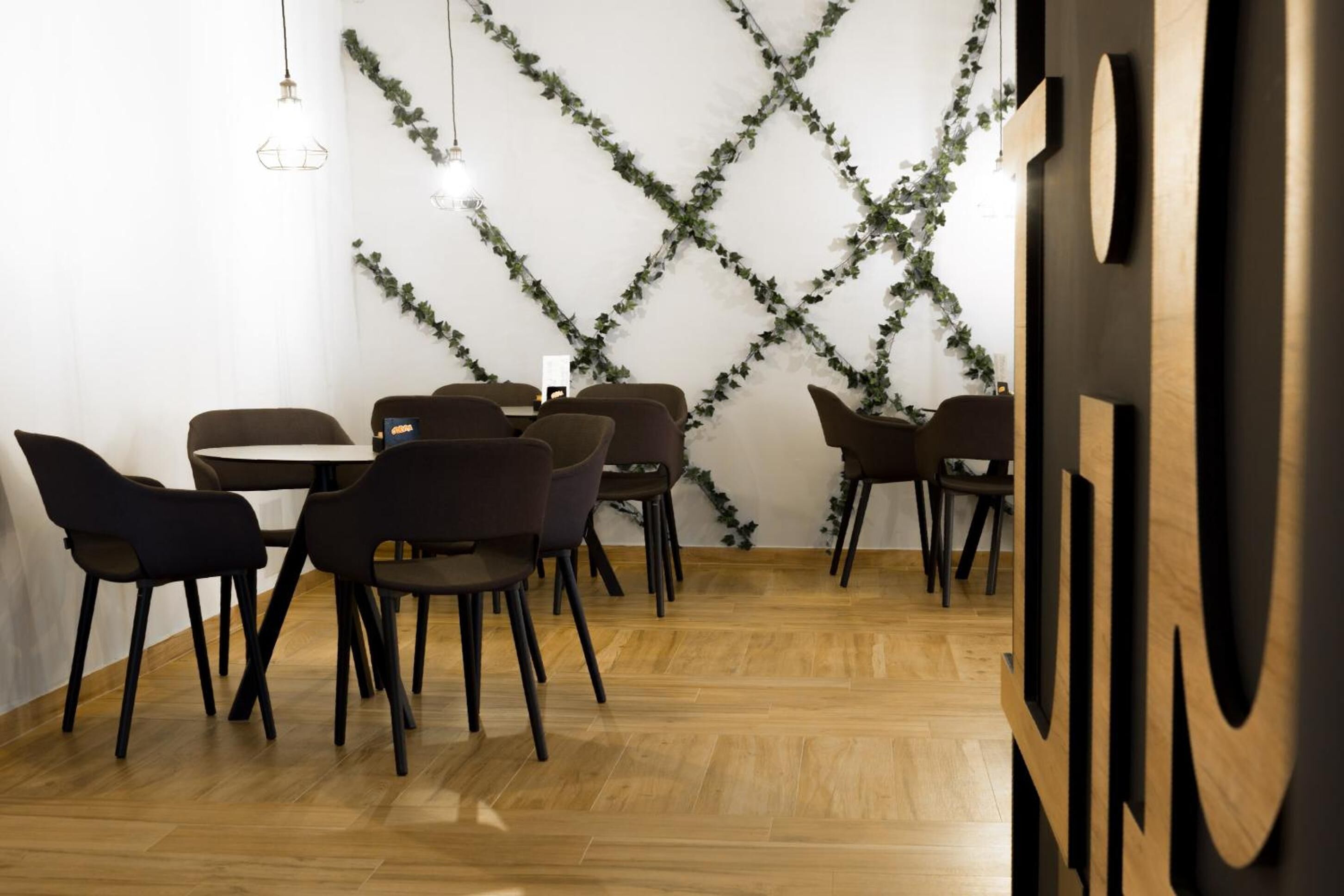 Un espace repas doté d’un plancher en bois, de chaises noires et d’une table blanche.