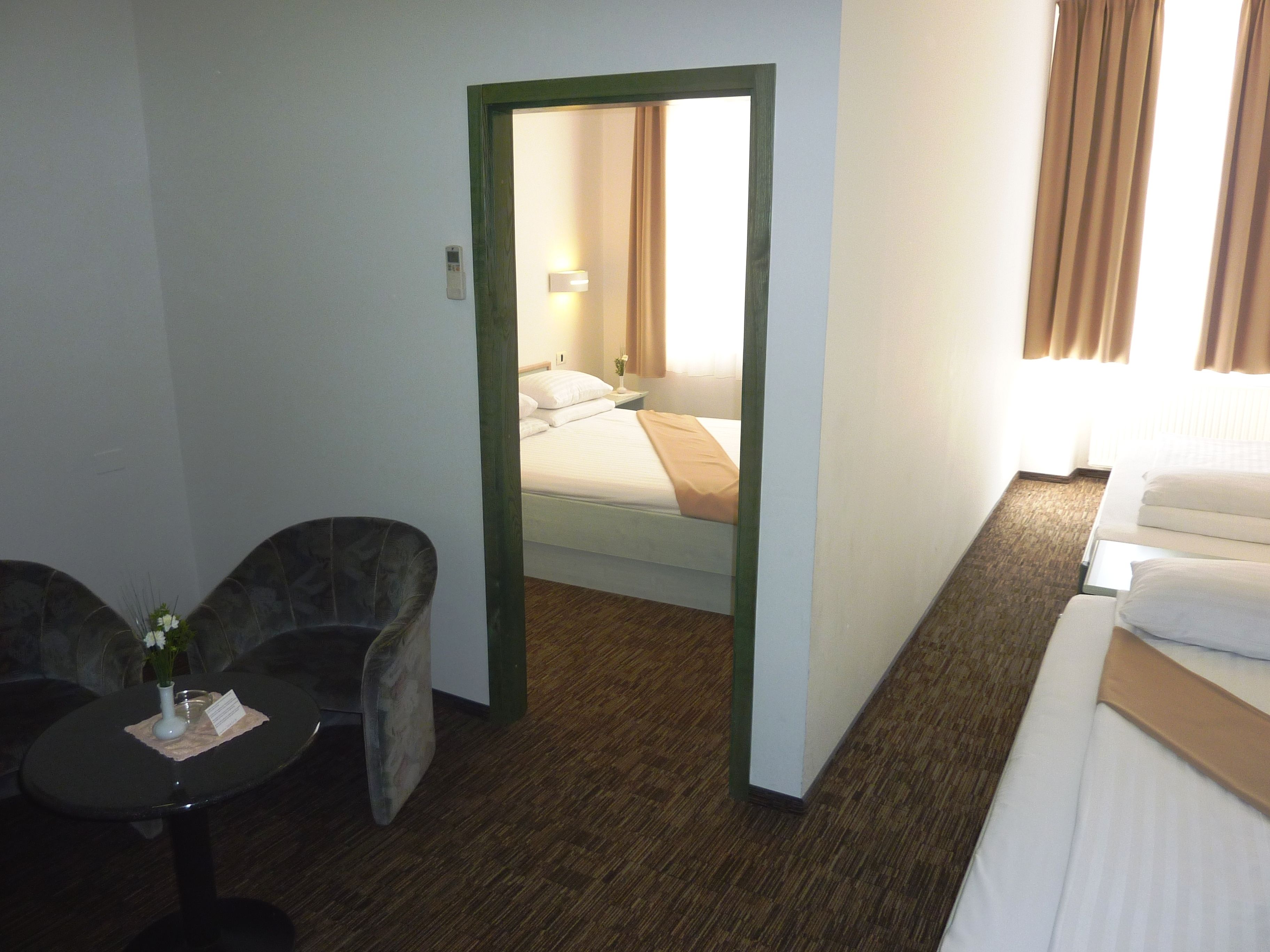 Una habitación de hotel con una cama, una mesita con un florero y una silla.