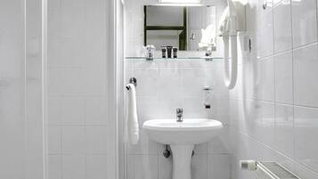 Un baño moderno con cabina de ducha de vidrio, lavamanos pedestal y radiador.