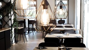 Un interior de restaurante moderno con lámparas colgantes hexagonales, mesas de madera y sillas negras.