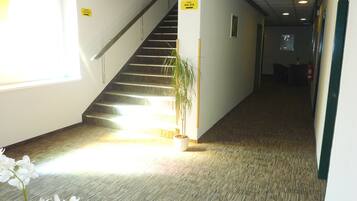 Ein Flur mit Treppe, Blumentopf und Wegweisern.