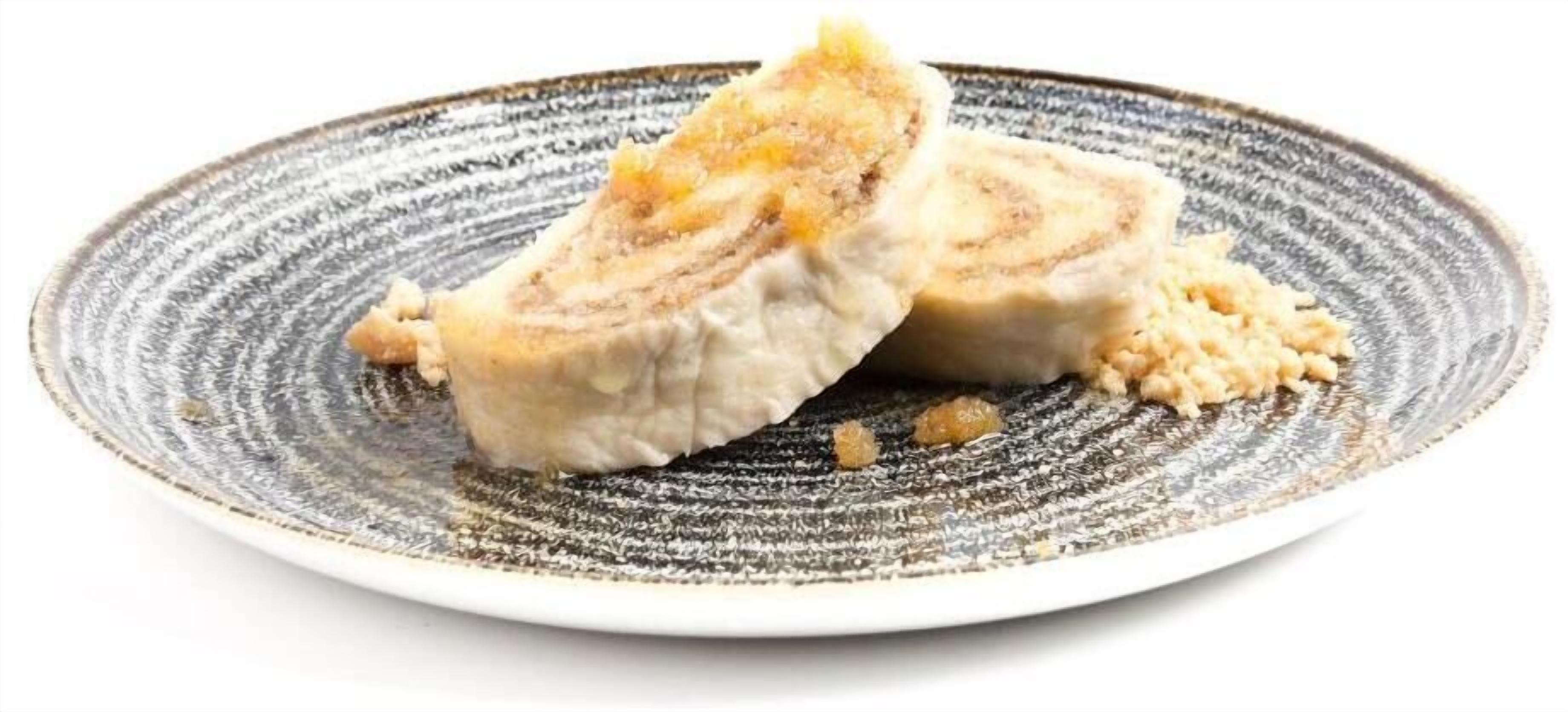 A plate with two pieces of rolled meat and some crumbs.