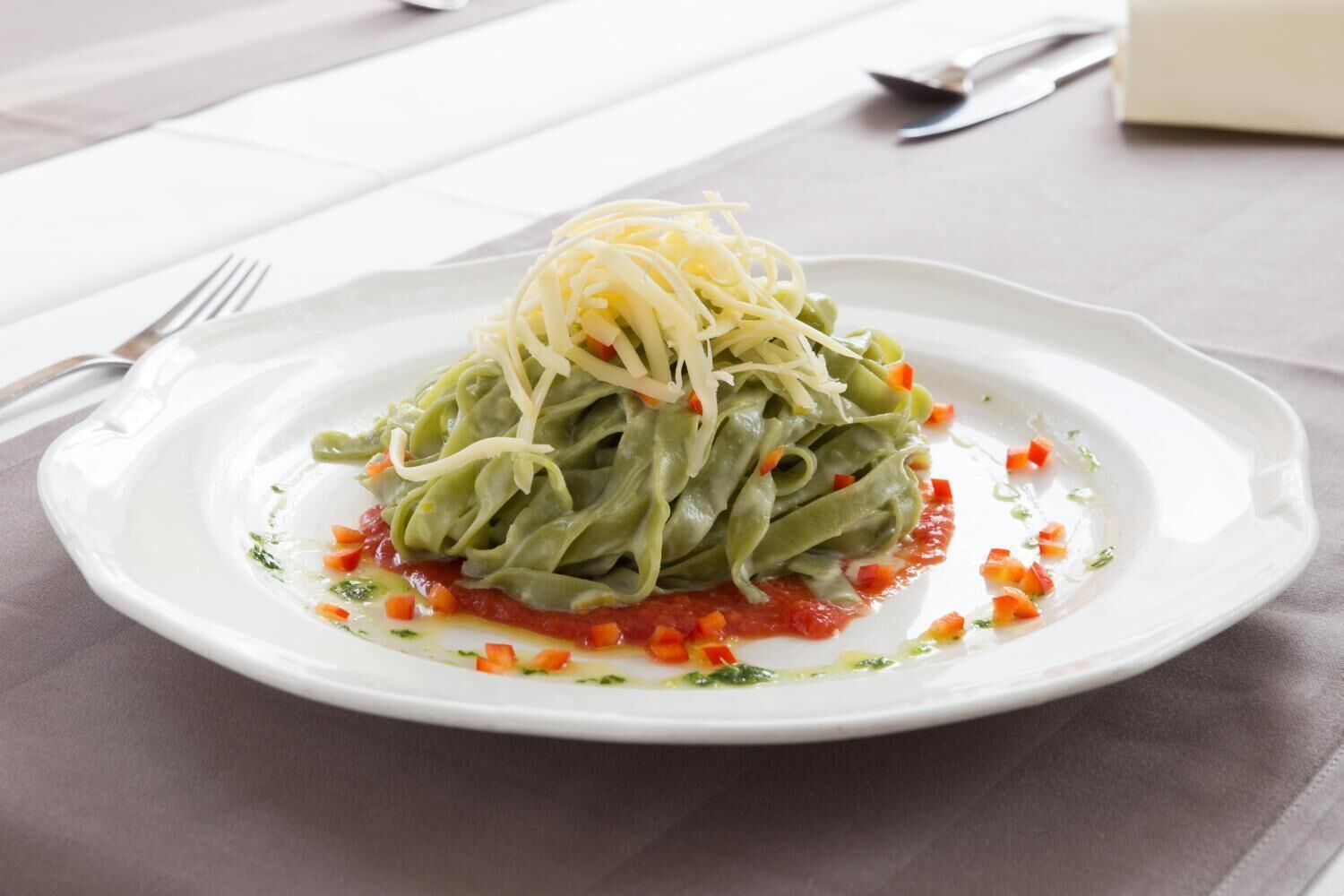 Un plato de pasta con salsa de tomate y queso rallado sobre un plato blanco.