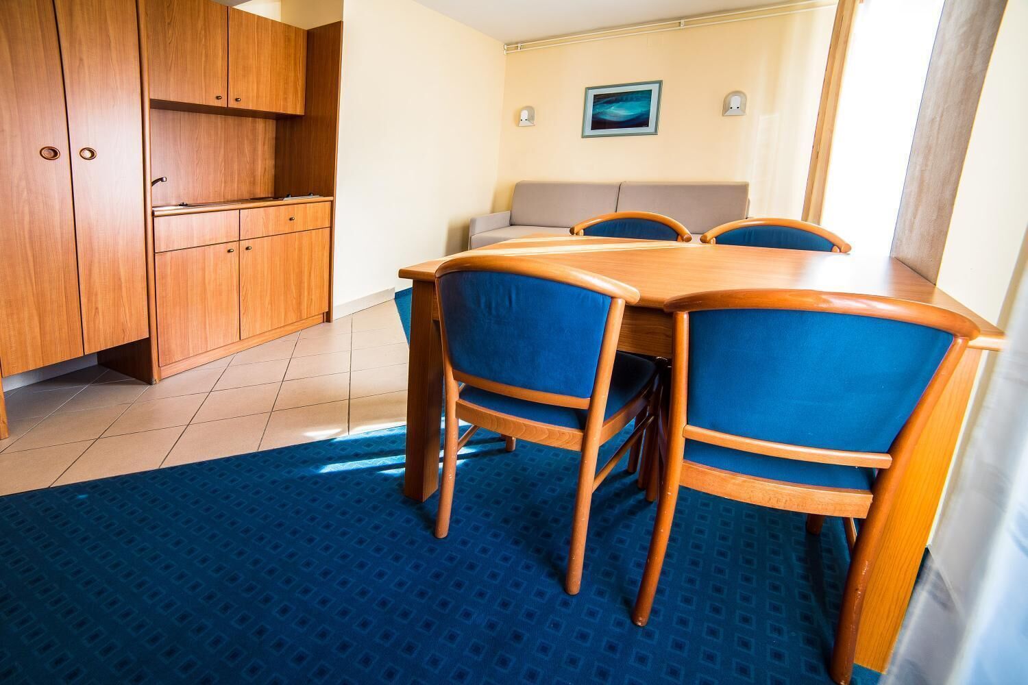 Una habitación compacta con una mesa de madera y sillas, un sofá y un armario.