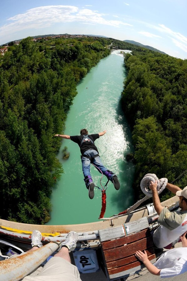 A person bungee jumping from a bridge over a river surrounded by dense greenery. - Hotel Sabotin (Nova Gorica)